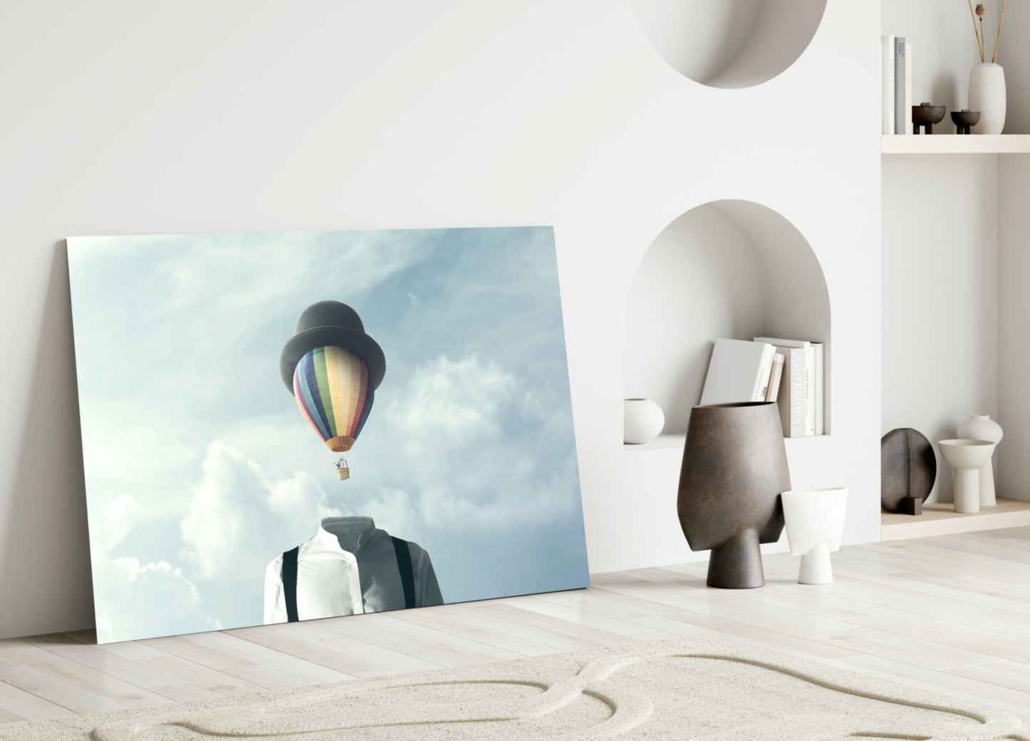 Glass wall art leaning against white wall showing man with bowler hat gazing at colorful hot air balloon in cloudy sky.