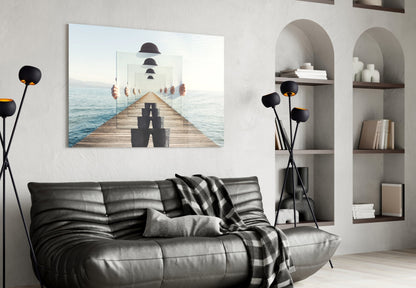 Surreal recursive pier artwork displayed on white wall above black leather sofa with bookshelves and decorative black flowers nearby.