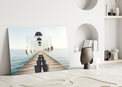 Surreal glass wall art leaning against white wall in minimalist room, showing wooden pier with recursive bowler hats and figure, ocean background.