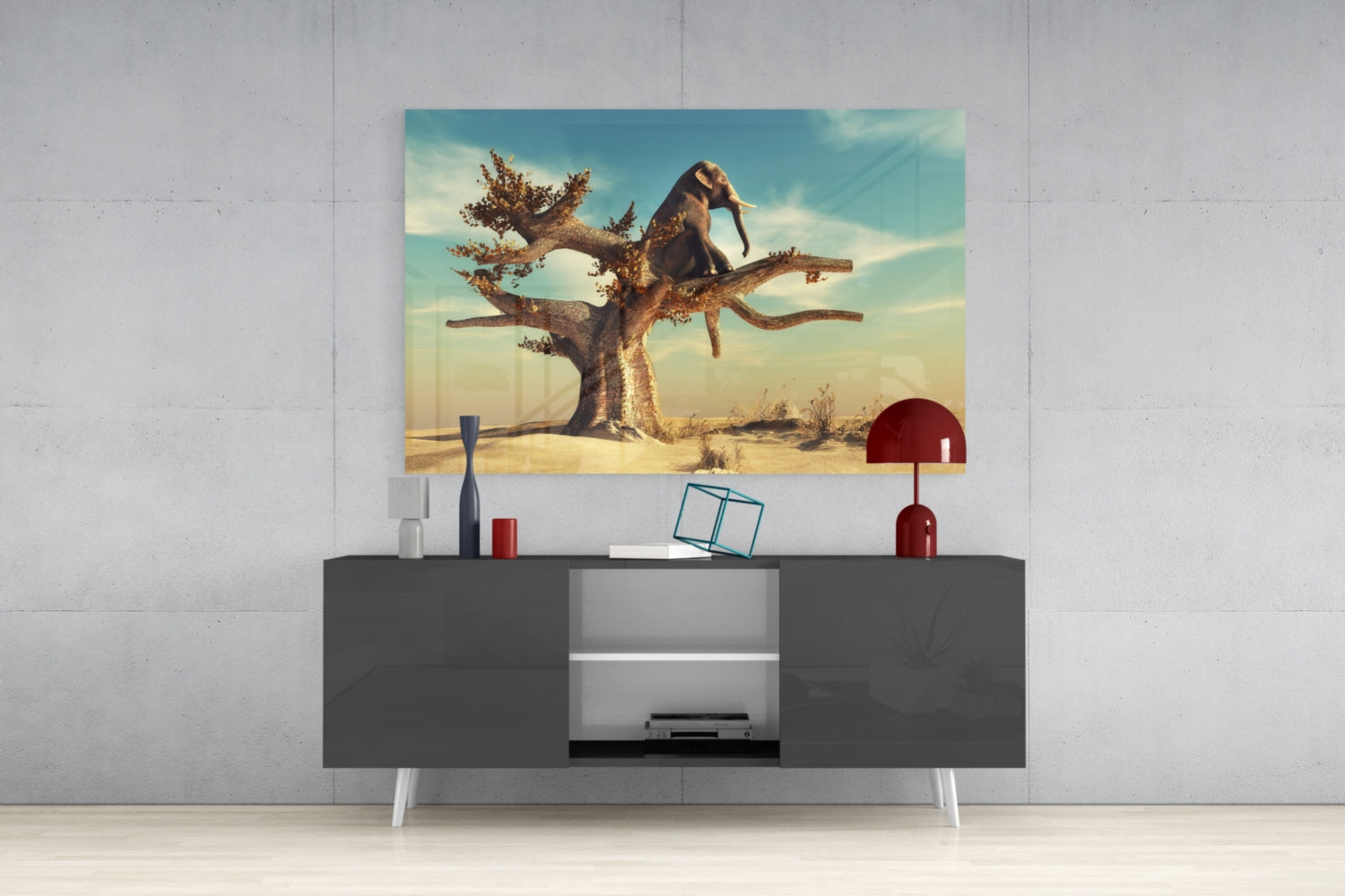 Thinking Elephant Glass Wall Art displayed above a dark gray media console, showing a desert landscape with an elephant perched on a gnarled tree against a turquoise sky.