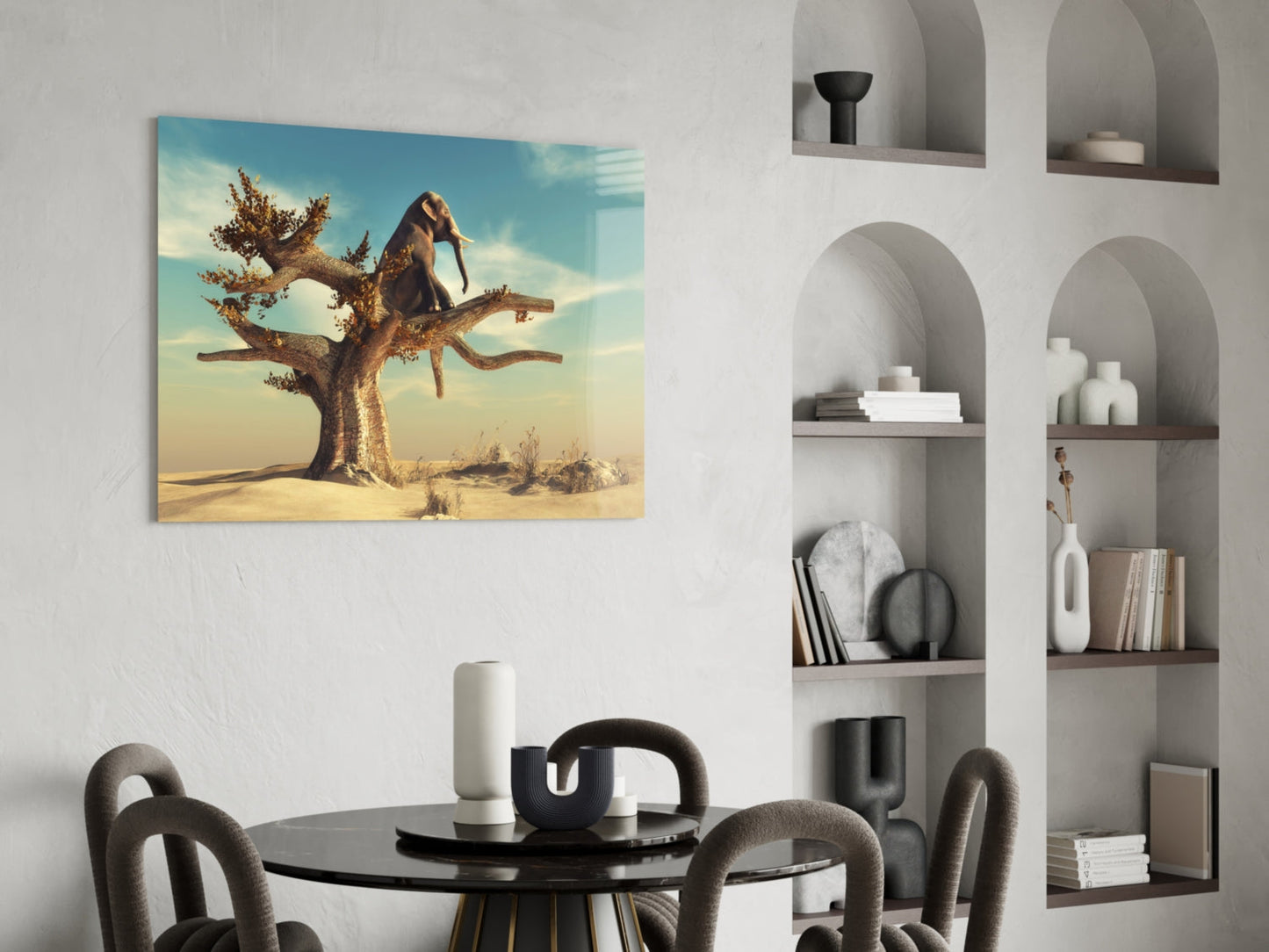 Glass wall art depicting an elephant perched on a gnarled tree in a desert landscape displayed above a round dining table.