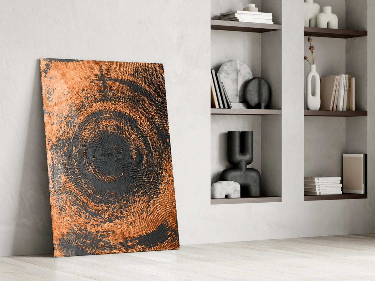 Copper spiral swirl glass wall art leaning against white wall beside built-in shelving with decorative objects.