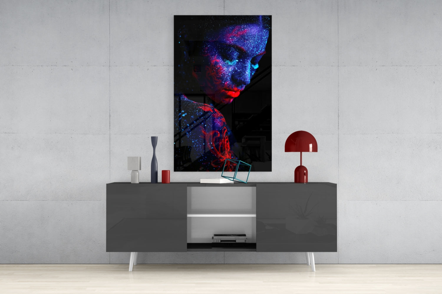 Serenity Glass Wall Art displayed above a gray console table, showing an abstract figure with blue and red luminescent particles against black background.