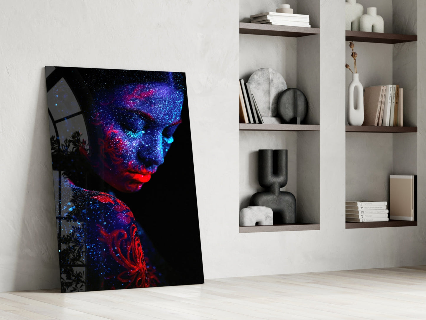 Vibrant neon portrait glass art leaning against white wall beside built-in shelving with decorative objects and books.