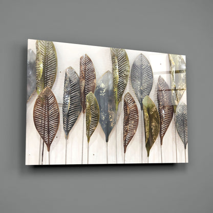 Angled view of glass wall art displaying metallic feather designs in gold, bronze, and silver tones on cream background, mounted on gray wall.
