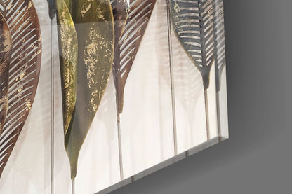 Close-up angled view of glass feather wall art showing gold, bronze, and gray striped feathers with white mounting panel.
