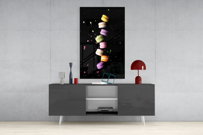 Colorful macarons in yellow, pink, and purple arranged vertically on black glass art displayed above a gray media console.