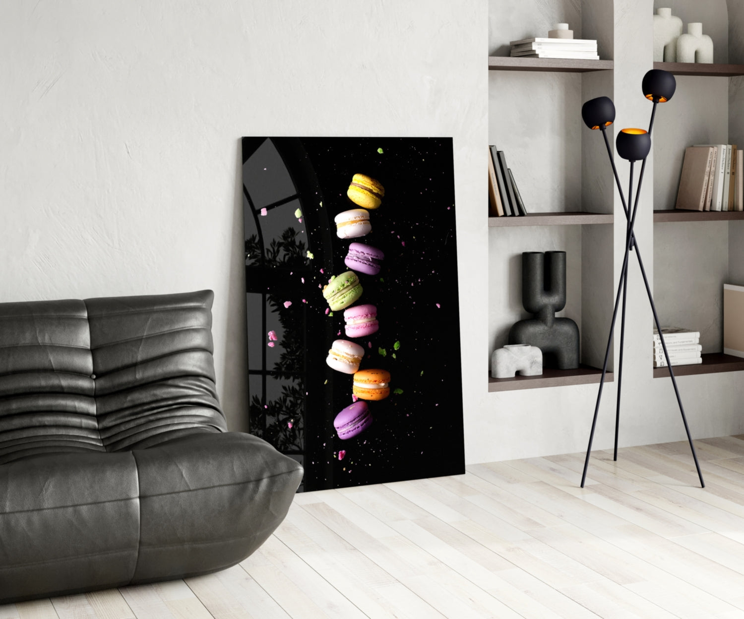 Colorful macarons arranged vertically on black glass art displayed in modern living room with gray sofa and shelving.