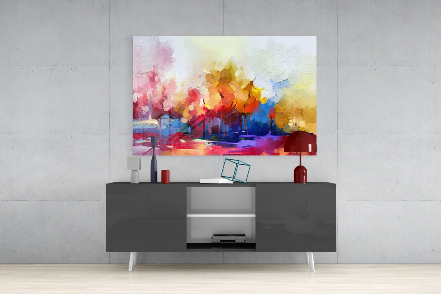 Colorful abstract watercolor landscape artwork with pink, yellow, orange, and blue tones displayed above a dark gray media console in a modern interior setting.