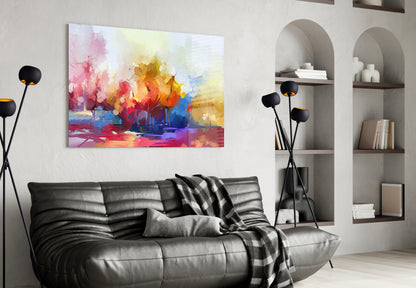 Abstract Trees Glass Wall Art displaying vibrant multicolored watercolor landscape with pink, yellow, orange and blue tones, displayed above black leather sofa in modern living room.