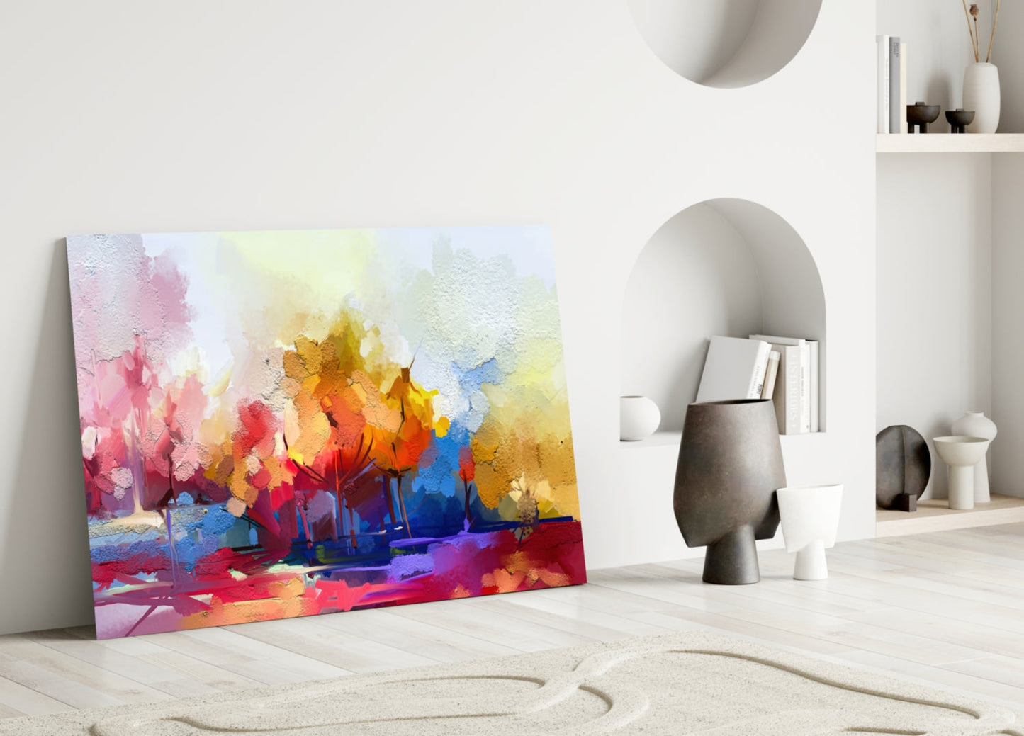 Vibrant abstract trees glass wall art leaning against white wall in minimalist interior with sandy floor and sculptural decor.