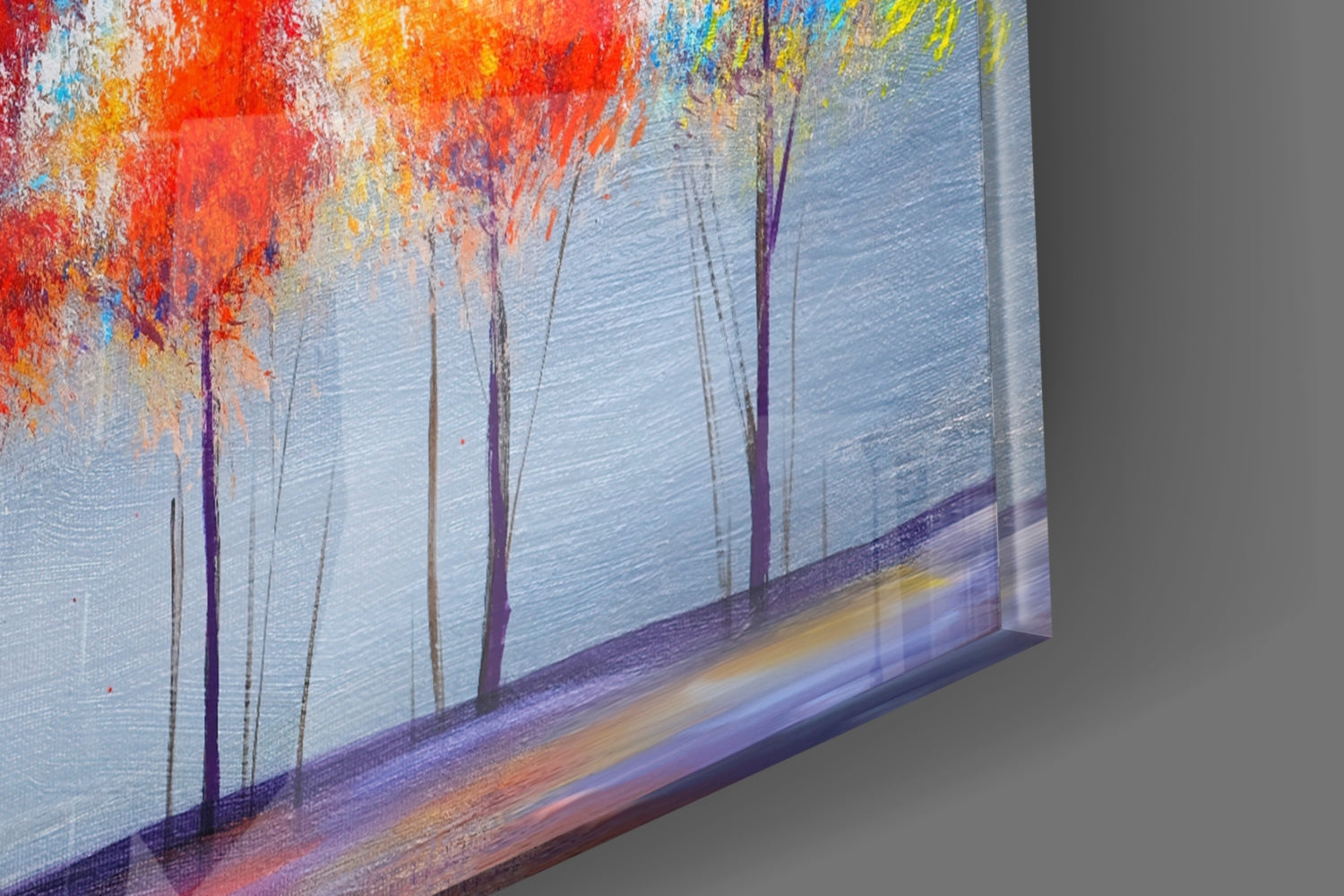 Angled side view of glass wall art showing silhouetted trees against blue water with vibrant red and orange sky gradient.