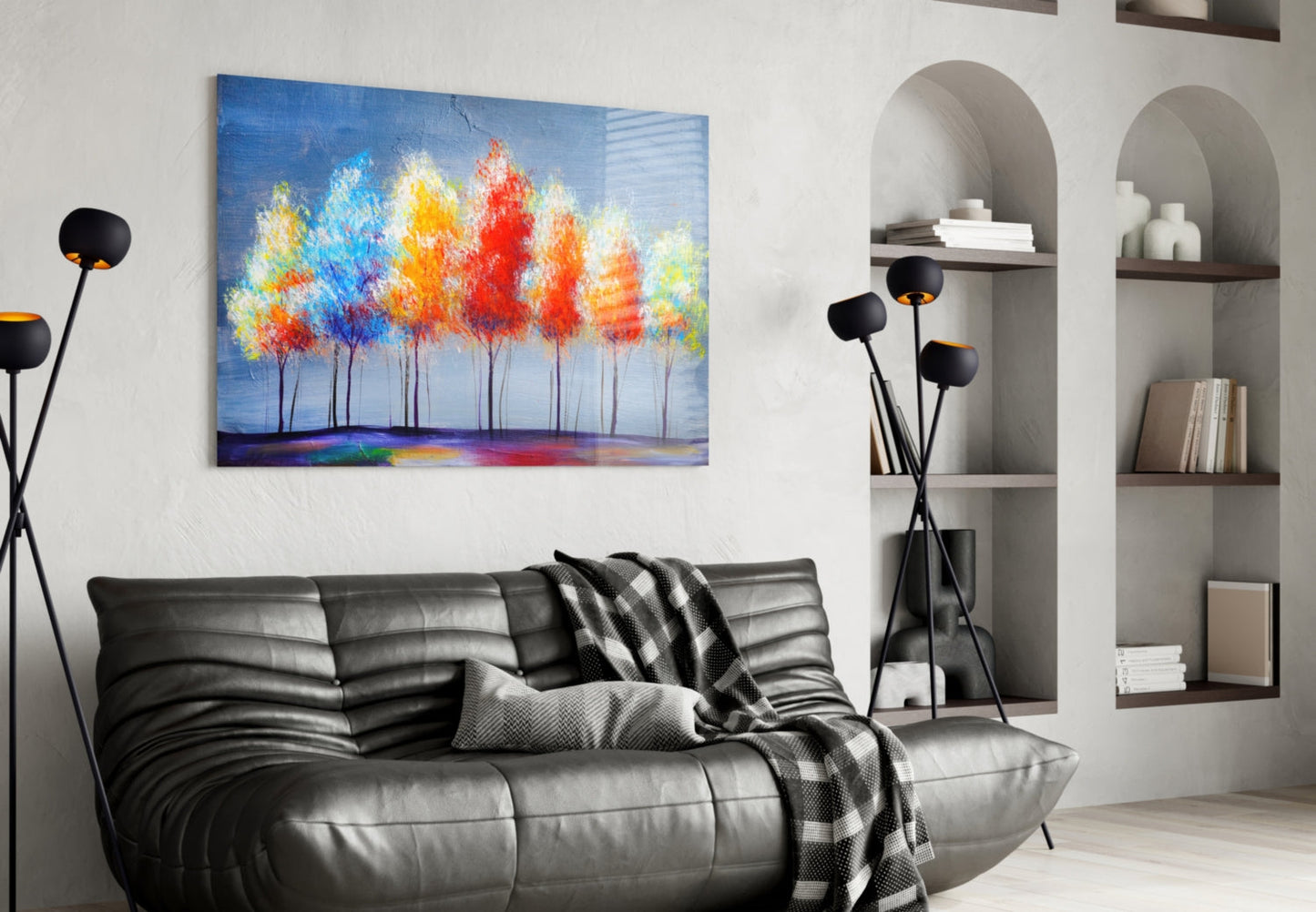 Colorful painted trees glass wall art hanging above black leather sofa in modern living room with arched shelving.