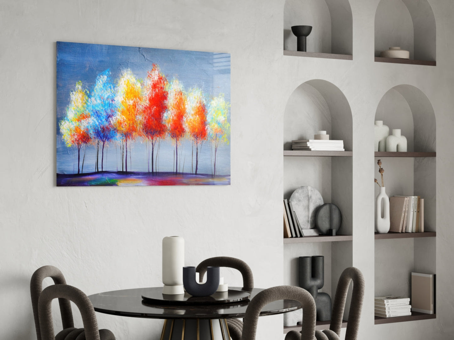 Colorful abstract tree painting with red, orange, and blue foliage displayed on white wall above black dining table.