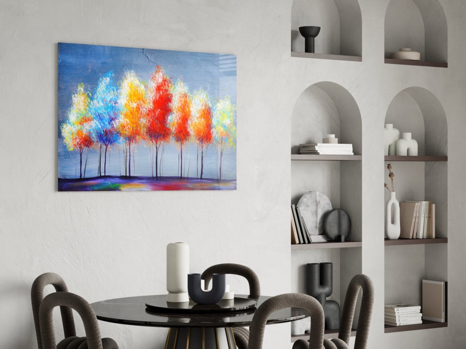 Colorful abstract tree painting with red, orange, and blue foliage displayed on white wall above black dining table.