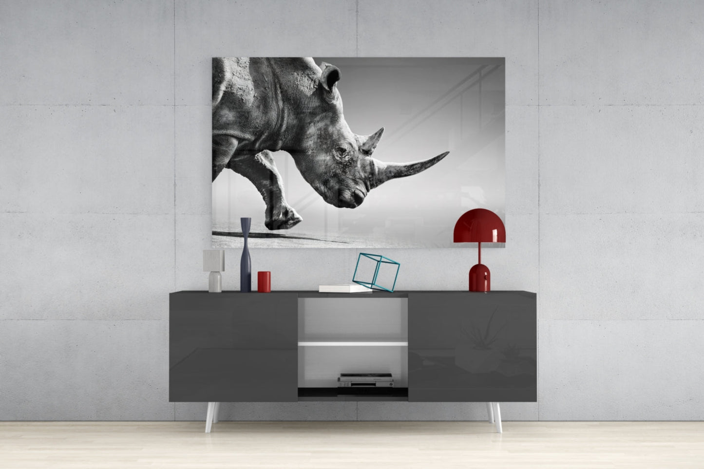Black and white glass wall art of a rhino's head displayed above a gray modern console table with red decorative accents.