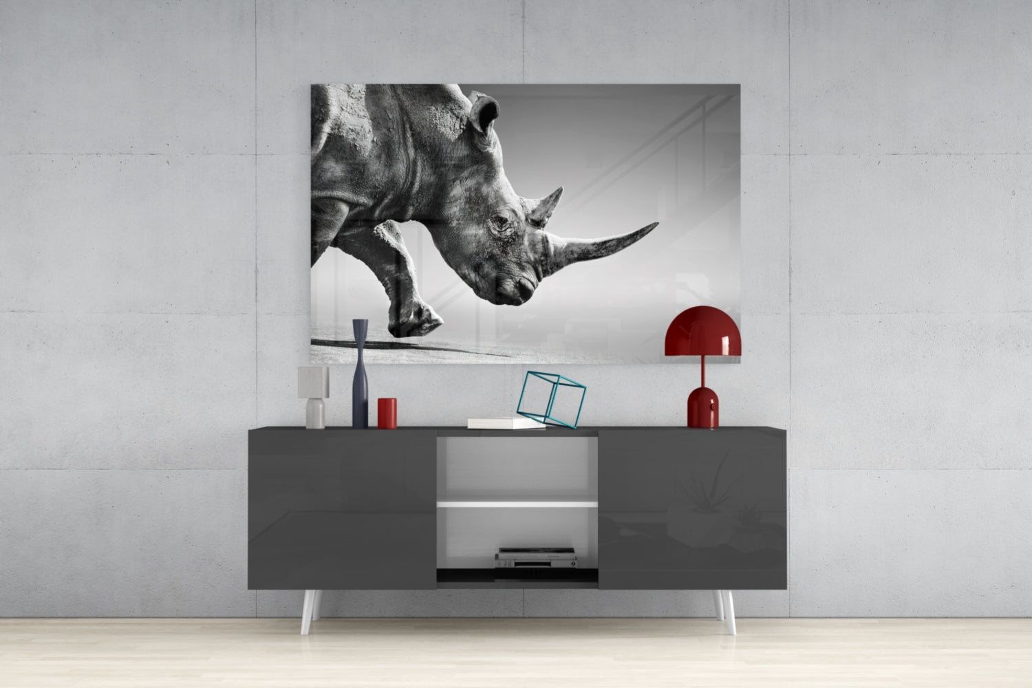 Black and white glass wall art of a rhino's head displayed above a gray modern console table with red decorative accents.