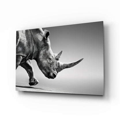 Black and white photograph of a rhinoceros in profile on glass wall art, showing detailed texture and side view against neutral background.