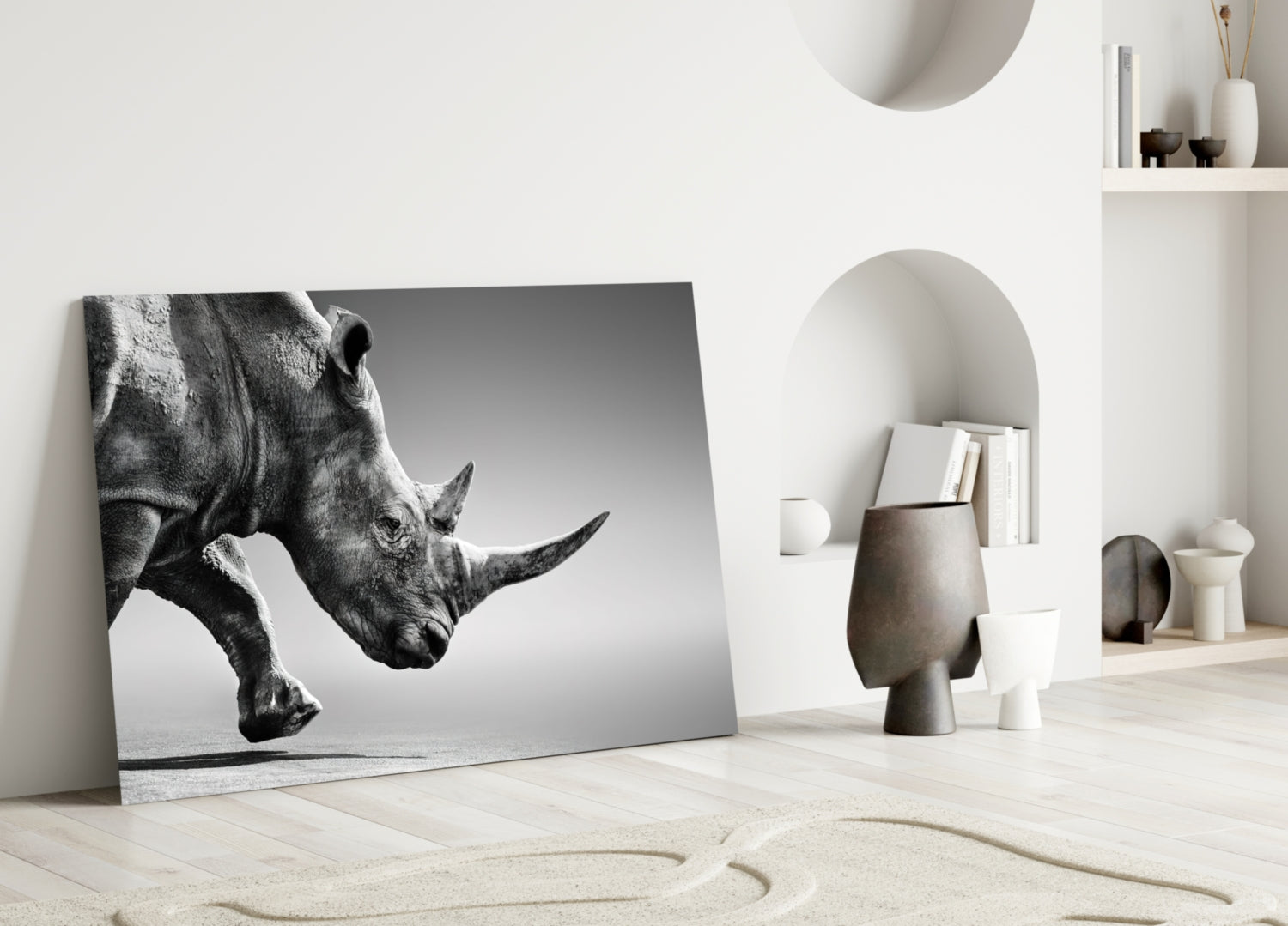 Black and white rhino portrait glass wall art leaning against white wall in minimalist interior setting.