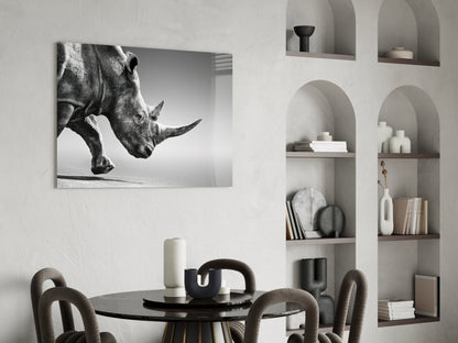 Black and white glass wall art of a rhino's head displayed above a dining table in a minimalist interior setting.