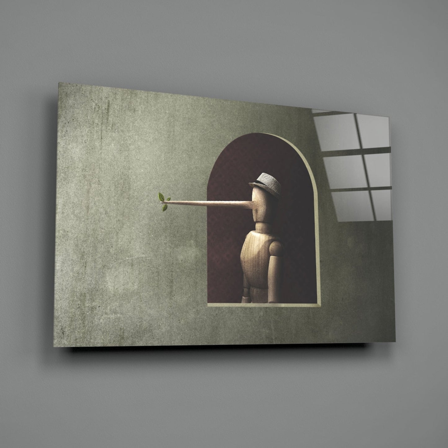 Wooden figure with extended nose holding small green leaf, viewed through arched window opening in textured green wall panel with gridded window frame.