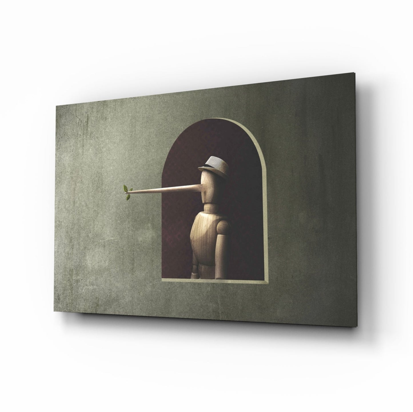 Wooden Pinocchio figure with extended nose displayed in arched niche on textured sage green glass panel, angled three-quarter view.