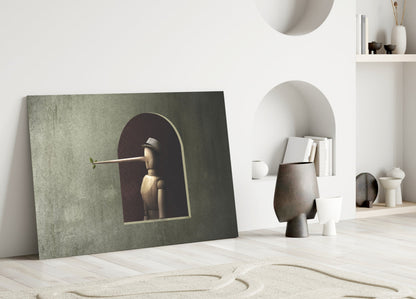 Pinocchio Glass Wall Art leaning against white wall displaying wooden puppet figure in arched alcove on textured green-grey background.