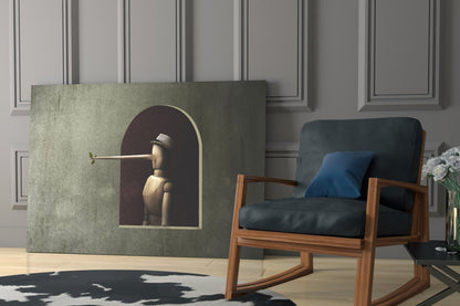 Pinocchio Glass Wall Art displayed in a modern interior with a wooden chair, showing a wooden figure in a hat within an arched frame against a sage-green background.