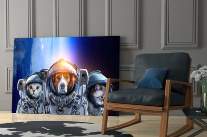 Space Team Glass Wall Art displaying three animals in astronaut suits against a blue cosmic background, displayed on a living room wall beside a wooden chair.
