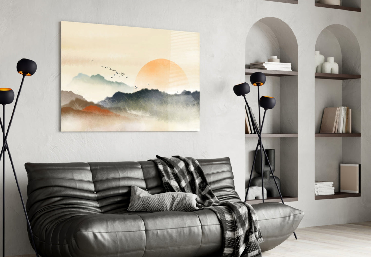 Abstract landscape glass wall art depicting misty mountains and orange sun displayed above black leather sofa in modern living room.