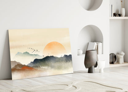 Abstract landscape glass art leaning against white wall displays misty mountains, orange sun, and flying birds in muted earth tones.