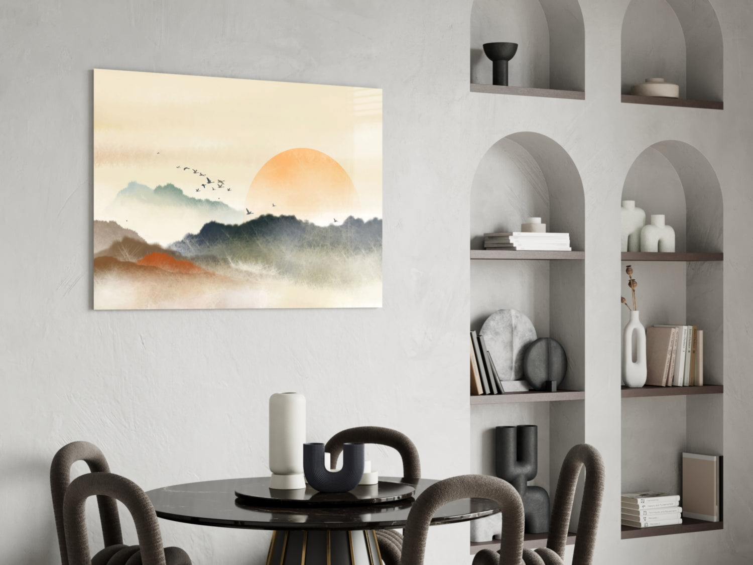 Abstract landscape glass art with orange sun, layered mountains, and flying birds displayed above dining table in modern interior.