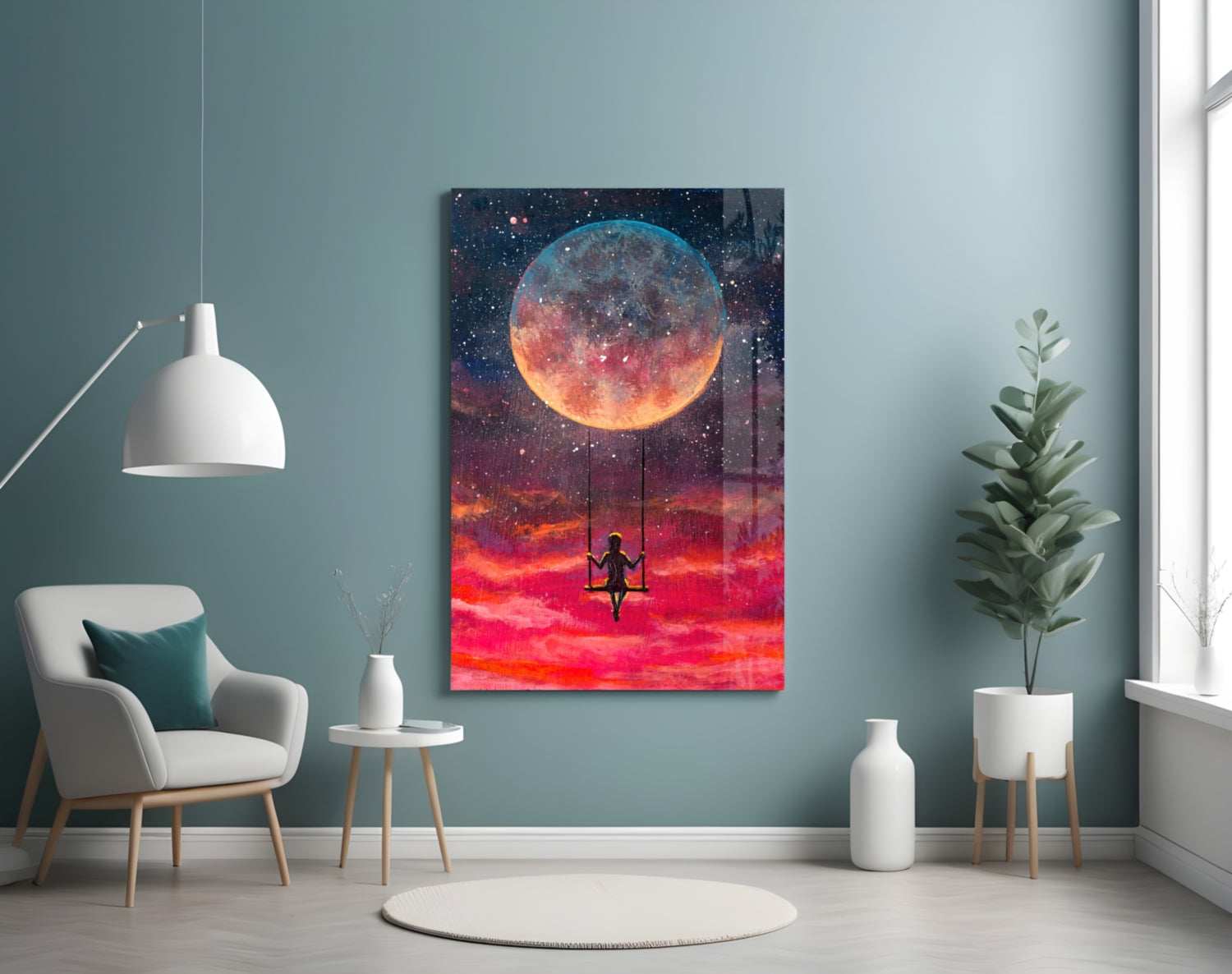 Freedom Glass Wall Art displayed on a teal wall above a white chair, showing a glowing moon and silhouetted figure on a swing against a red sky.