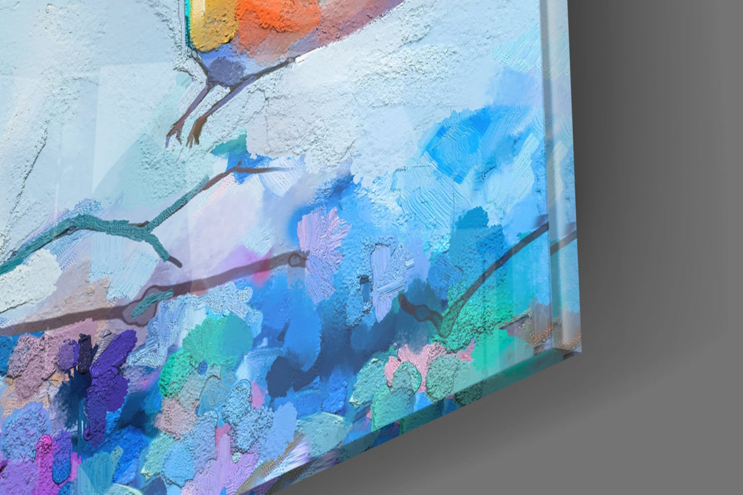 Close-up angled view of glass wall art featuring painted birds on branches with vibrant blue, purple, green, and orange colors against white background.