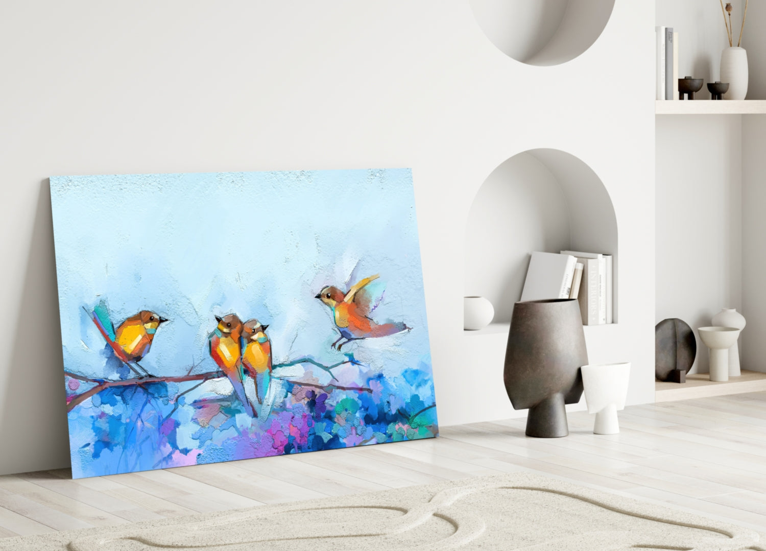 Colorful glass wall art depicting three orange and blue birds on a branch leans against white wall in minimalist interior.