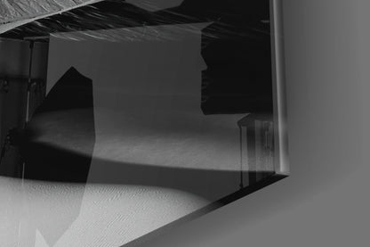 Black glass wall art panel displayed indoors showing silhouetted architectural forms against light background, angled view.