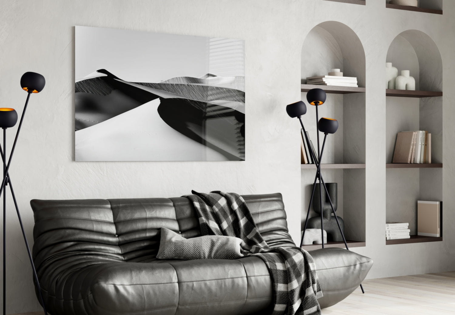 Black and white glass wall art depicting abstract curved forms displayed above a black leather sofa in a modern living room.