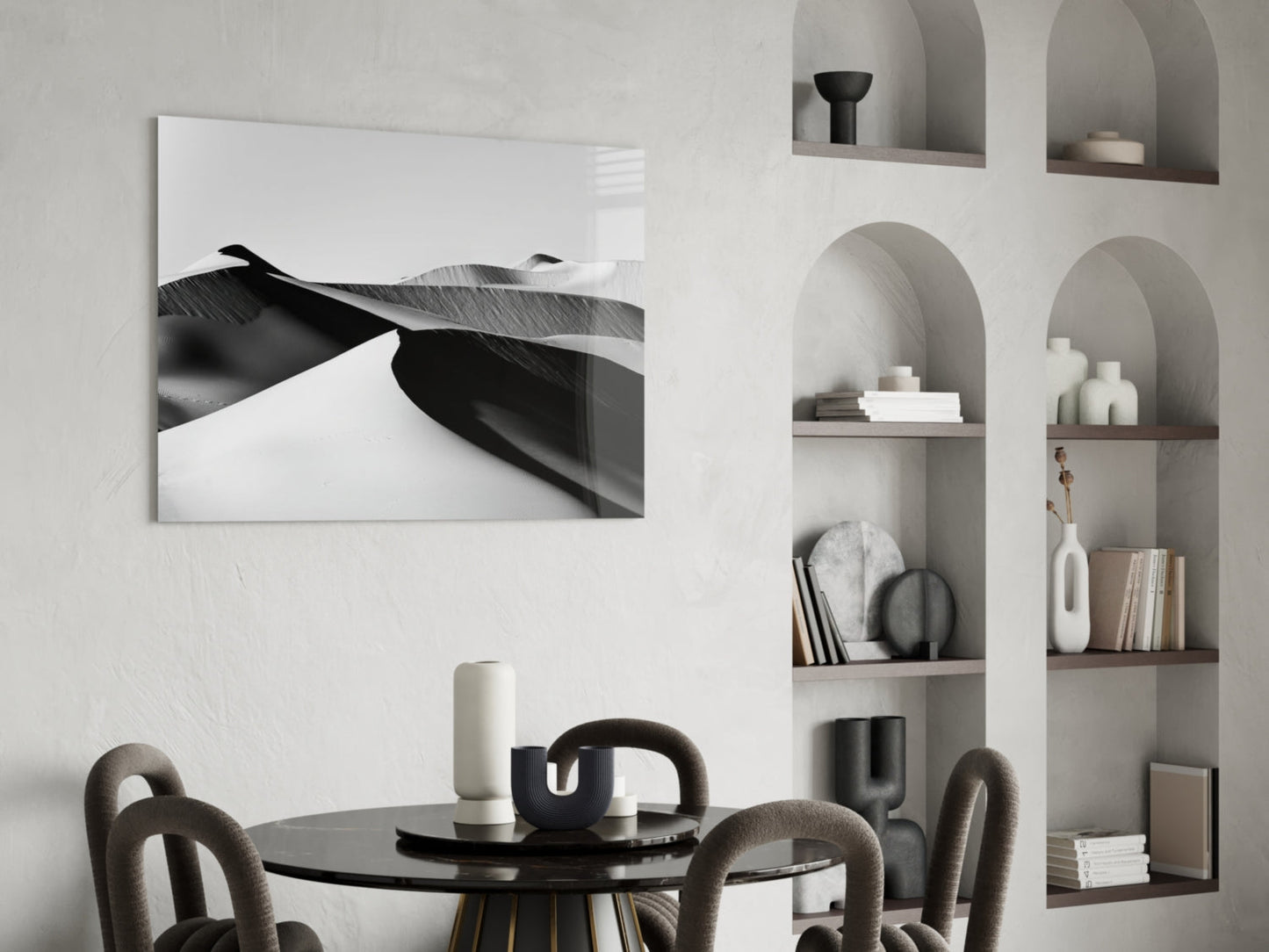 Black landscape glass wall art displaying abstract feather detail mounted above round black dining table with chairs in minimalist room.