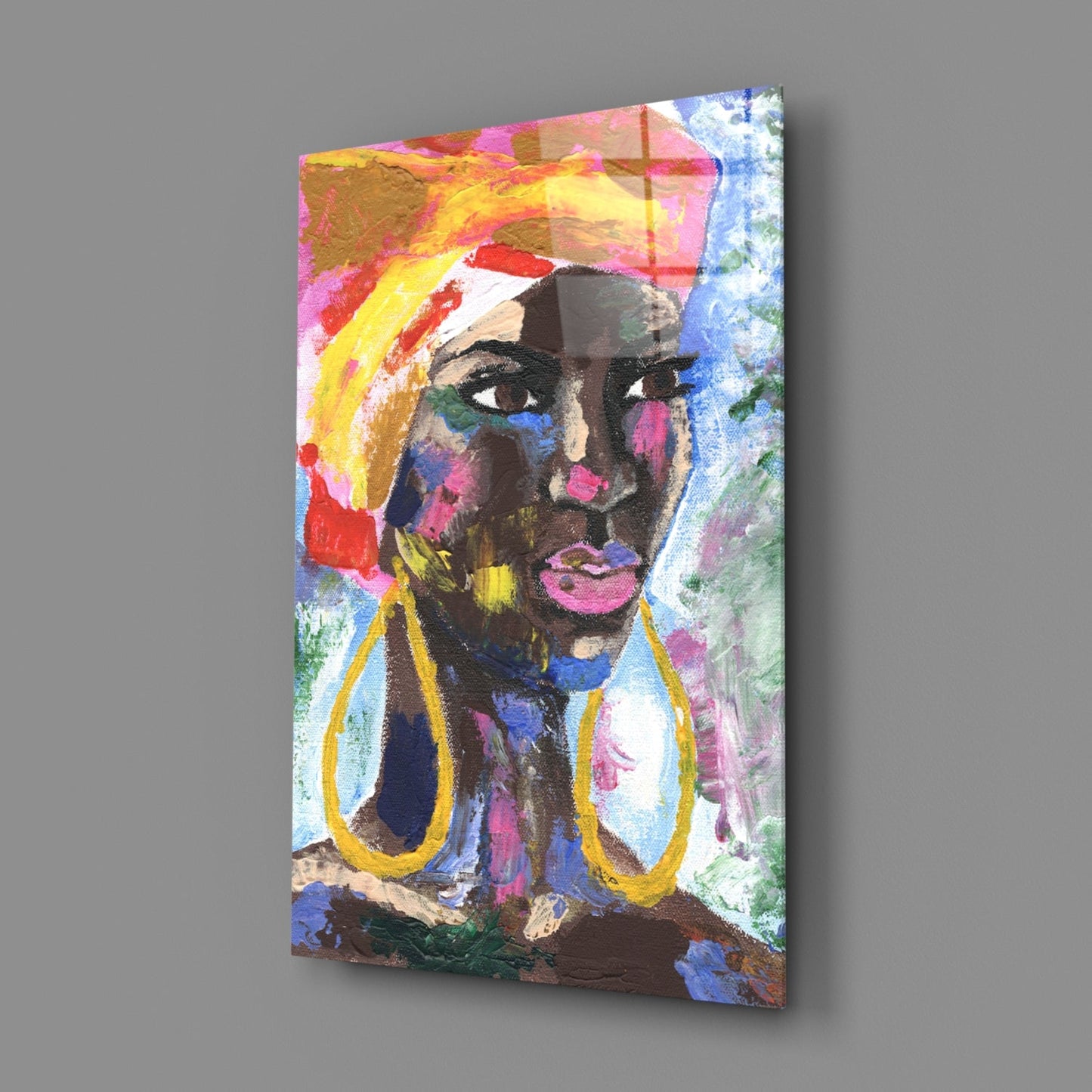 Angled view of a colorful glass wall art panel featuring an abstract portrait of a woman with vibrant paint strokes in pink, yellow, blue, and gold tones.