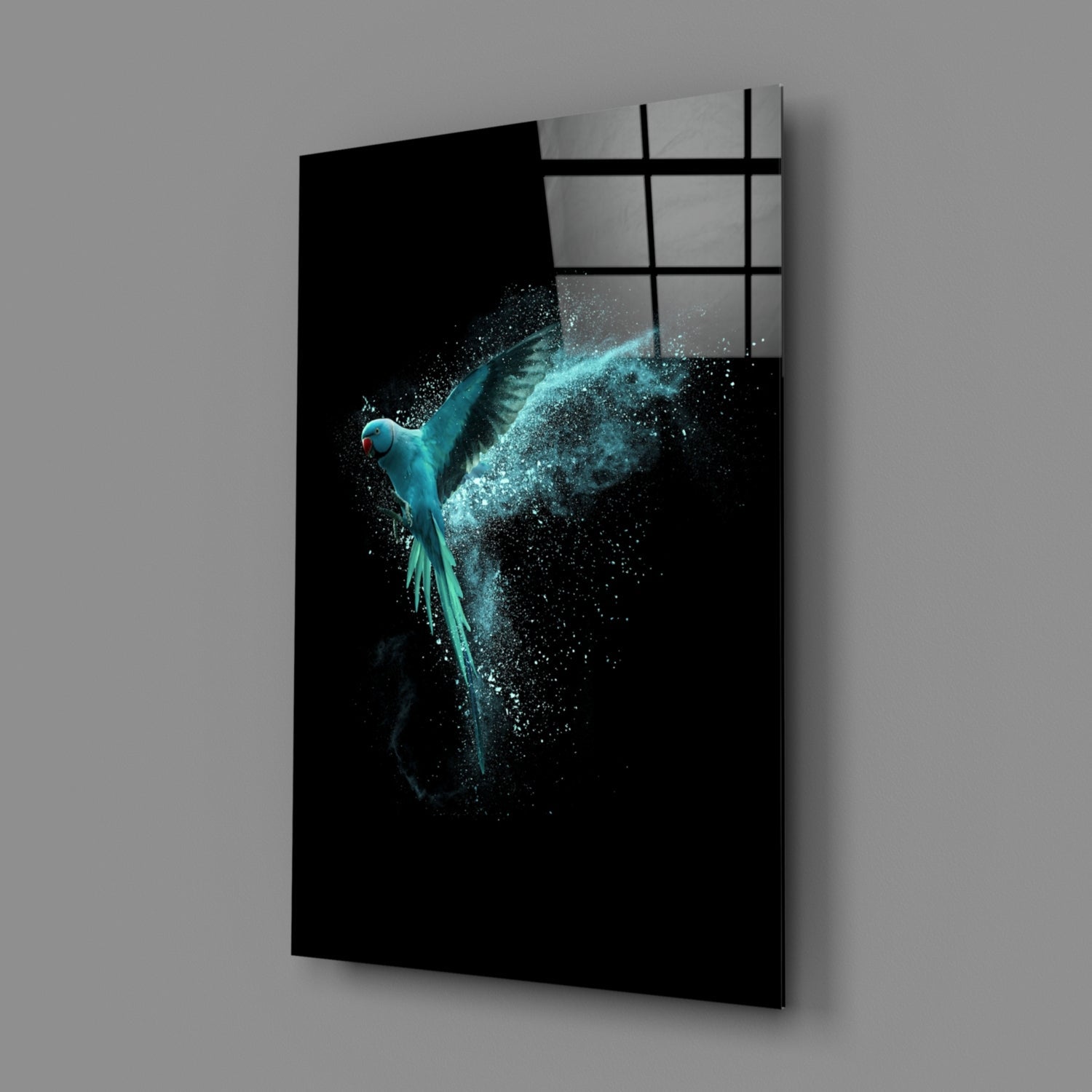 Turquoise parrot with dispersing particles on black glass panel, angled three-quarter view showing gridded window reflection above.