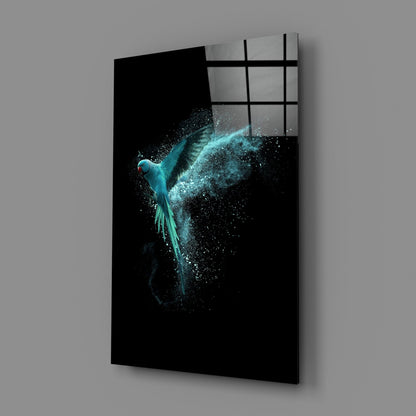 Turquoise parrot with dispersing particles on black glass panel, angled three-quarter view showing gridded window reflection above.