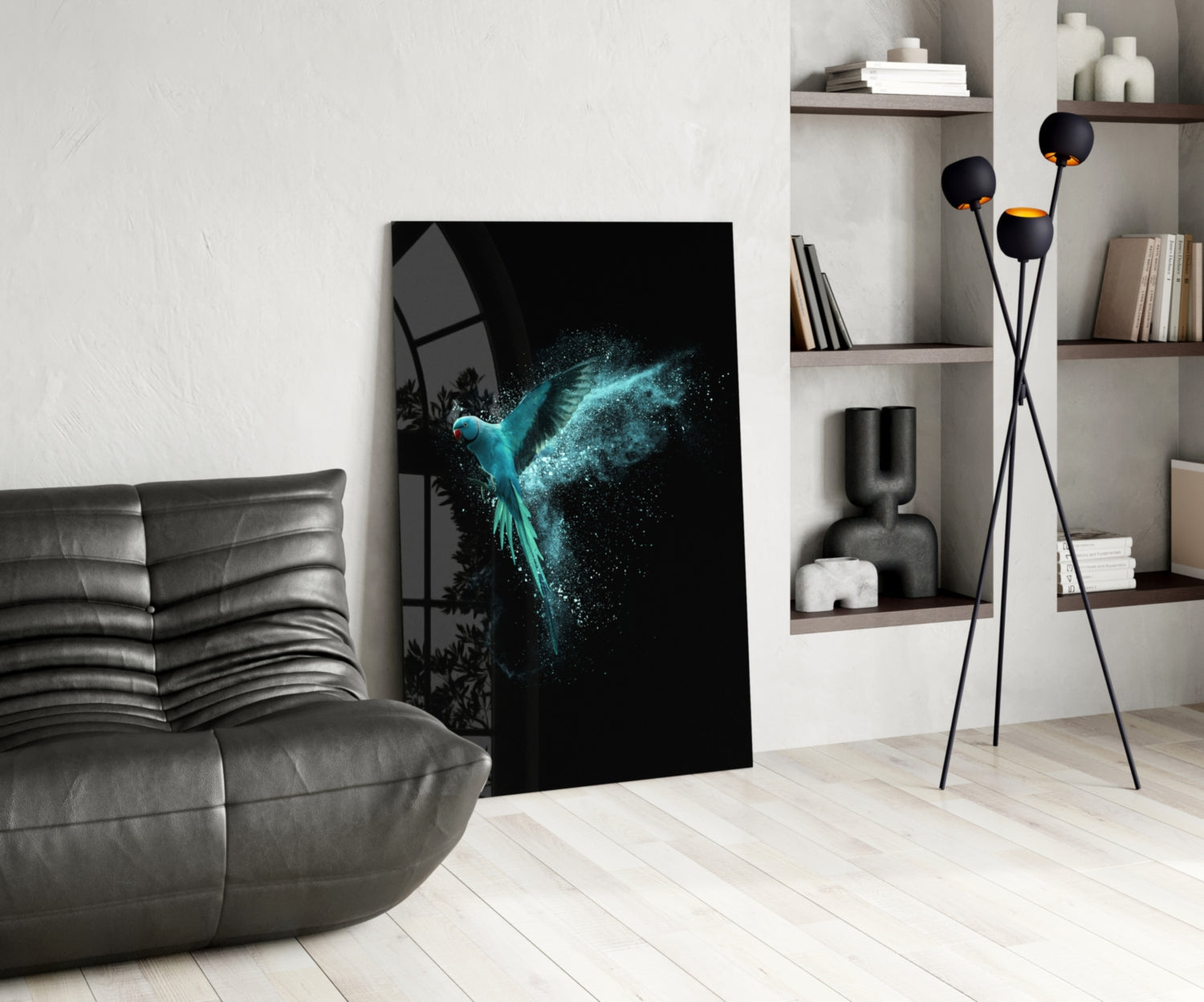 Luminous Parrot Glass Wall Art displayed leaning against white wall in modern living room with gray sofa and shelving.