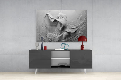 Monochromatic relief glass wall art depicting a woman's profile with flowing fabric, displayed above a dark console table with white legs and red decorative accessories.