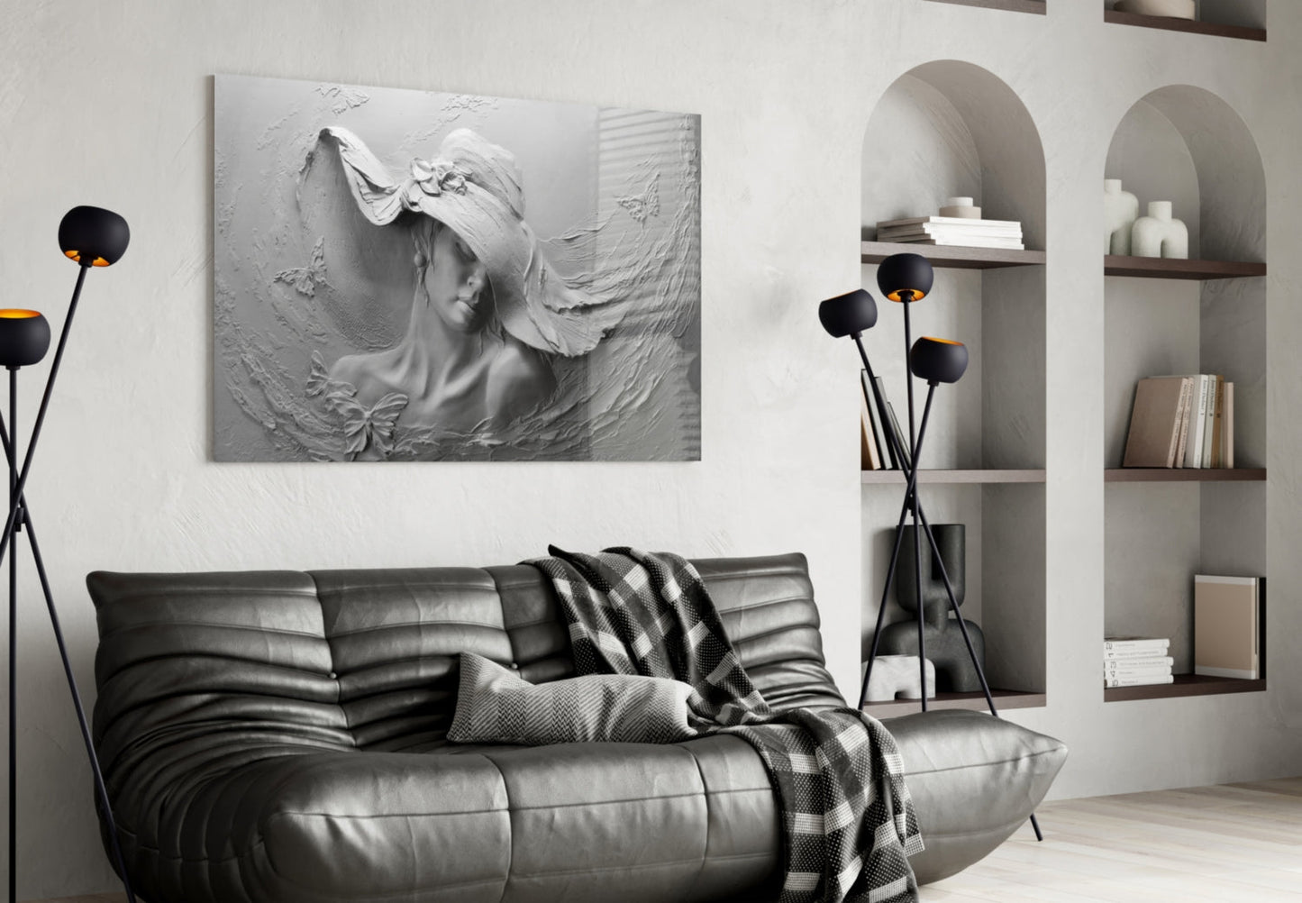 White textured relief sculpture of a woman's face with flowing hair and butterfly detail, mounted on wall above black leather sofa in modern living room.