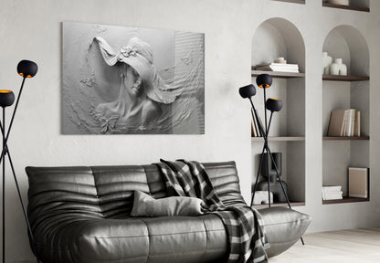White textured relief sculpture of a woman's face with flowing hair and butterfly detail, mounted on wall above black leather sofa in modern living room.