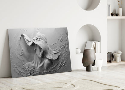 Gray relief glass wall art depicting a woman's profile with flowing hair displayed against a white interior wall with decorative shelving.