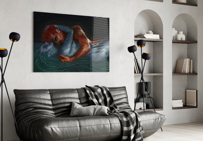 Glass wall art depicting a woman with red hair immersed in teal water, displayed above a black leather sofa in a modern living room.