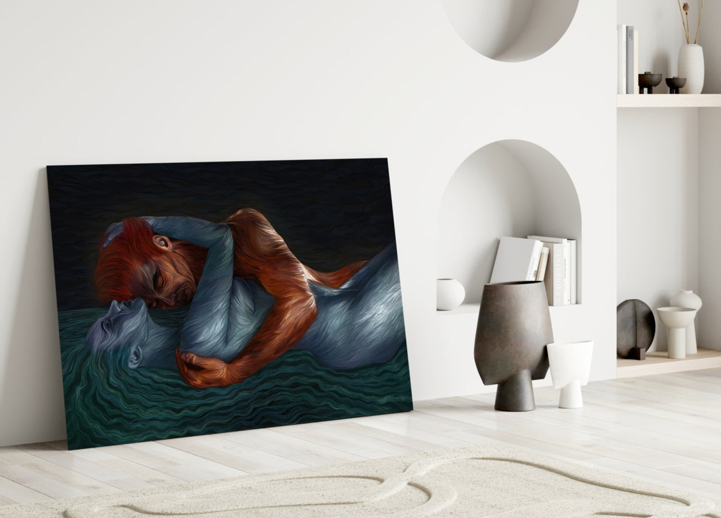 Glass wall art depicting a figure with reddish-brown hair in blue fabric reclining above dark teal water, leaned against white interior wall beside decorative objects.