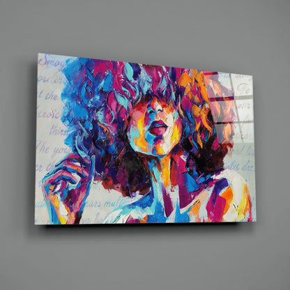 Colorful abstract portrait on glass wall art featuring vibrant blue, pink, orange, and purple brushstrokes with faint handwritten text overlay.