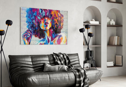 Vibrant pop art portrait canvas in blues, pinks, and yellows displayed above a black leather sofa in a modern living room.